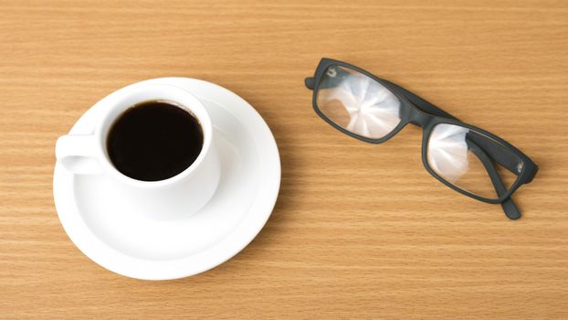 coffee cup and eyeglasses on wood background