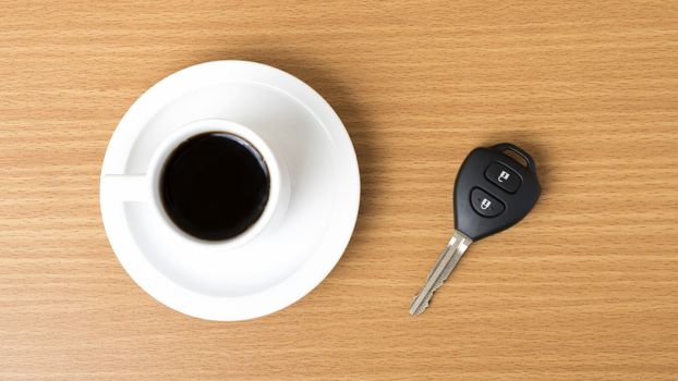 coffee cup and car key on wood background