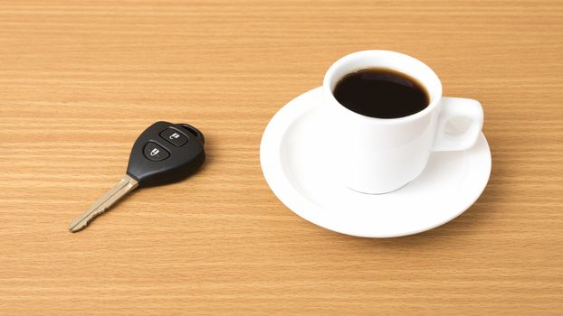 coffee cup and car key on wood background