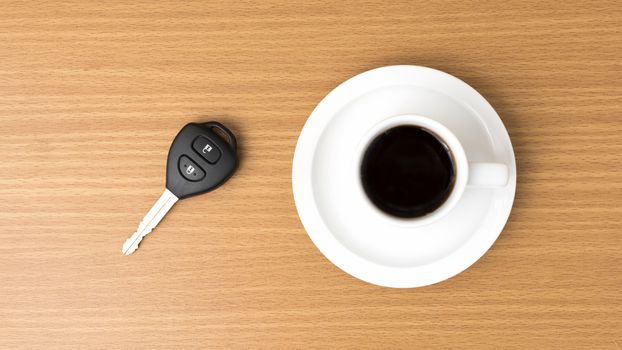 coffee cup and car key on wood background