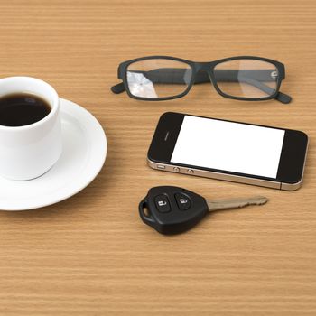 coffee cup and phone with car key on wood background