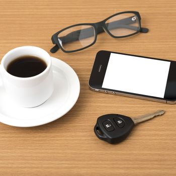coffee cup and phone with car key on wood background