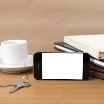 coffee cup with phone key and stack of book on wood background