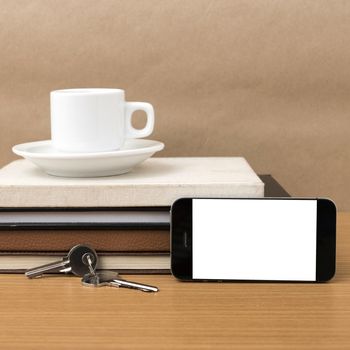 coffee cup with phone key and stack of book on wood background