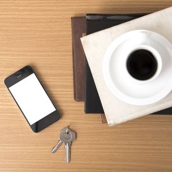 coffee cup with phone key and stack of book on wood background