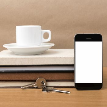 coffee cup with phone key and stack of book on wood background