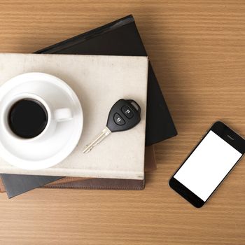 coffee cup with phone car key and stack of book on wood background
