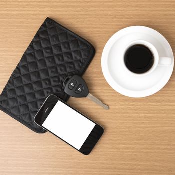 coffee cup with phone car key and wallet on wood background