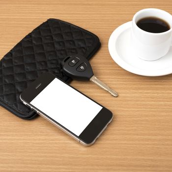 coffee cup with phone car key and wallet on wood background