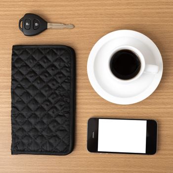 coffee cup with phone car key and wallet on wood background