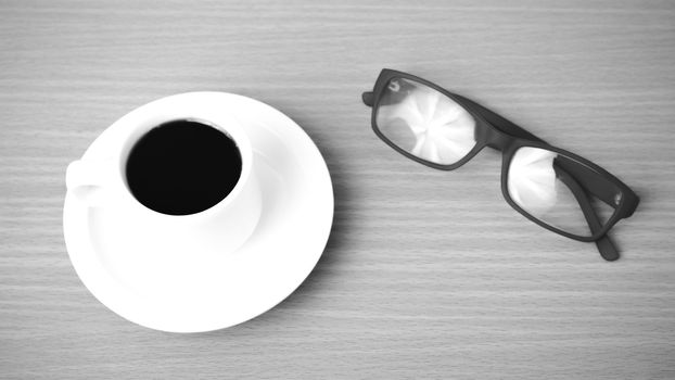 coffee cup and eyeglasses on wood background black and white color