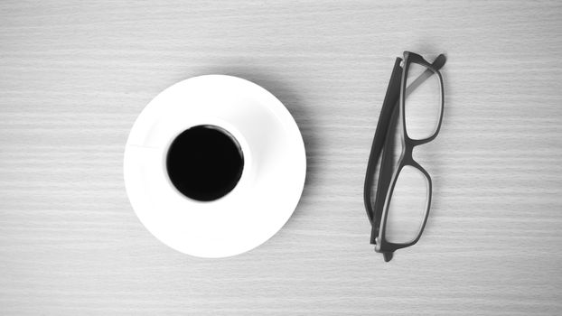 coffee cup and eyeglasses on wood background black and white color