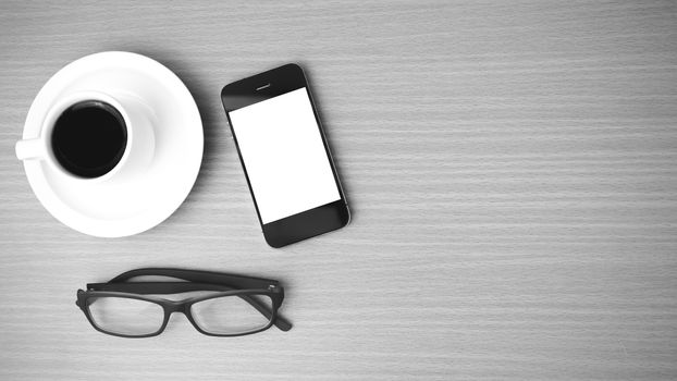 coffee cup and phone and eyeglasses on wood background  black and white color