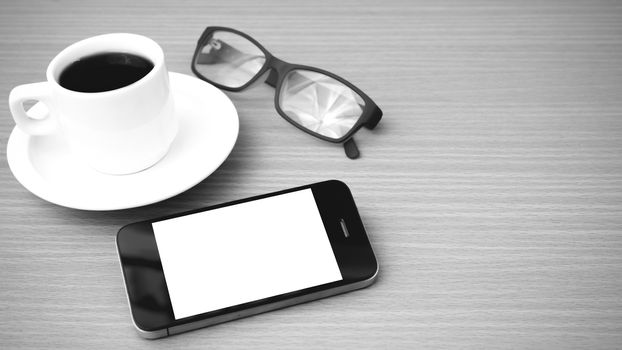 coffee cup and phone and eyeglasses on wood background  black and white color