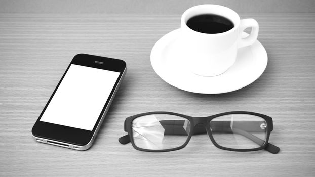 coffee cup and phone and eyeglasses on wood background  black and white color