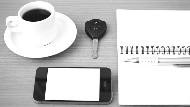 coffee cup with phone car key and notepad on  wood background black and white color