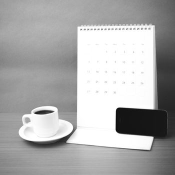 coffee cup and phone and calendar on wood background  black and white color