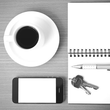 coffee cup with phone key and notepad on  wood background black and white color