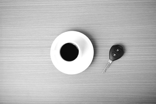 coffee cup and car key on wood background  black and white color