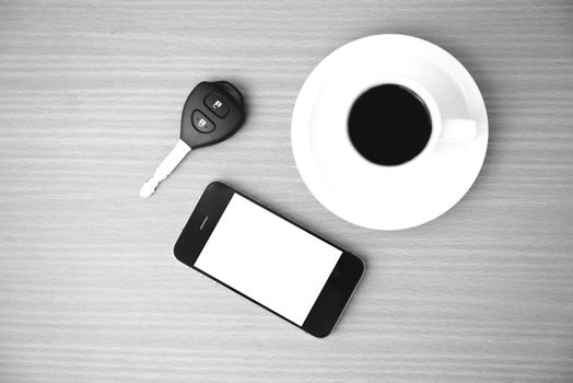 coffee cup and phone and car key on wood background black and white color