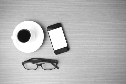 coffee cup and phone and eyeglasses on wood background  black and white color