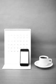coffee cup and phone and calendar on wood background  black and white color