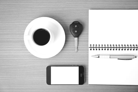 coffee cup with phone car key and notepad on  wood background black and white color