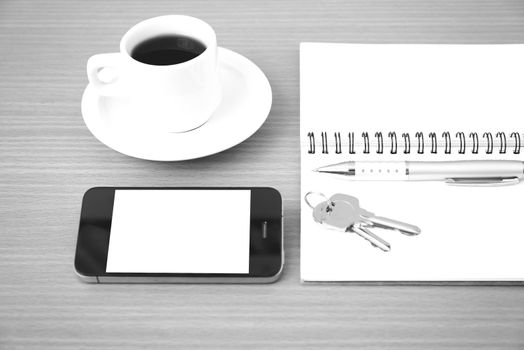 coffee cup with phone key and notepad on  wood background black and white color