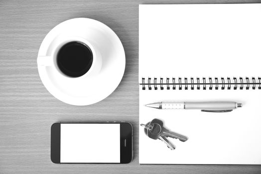 coffee cup with phone key and notepad on  wood background black and white color