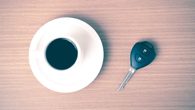 coffee cup and car key on wood background  vintage style