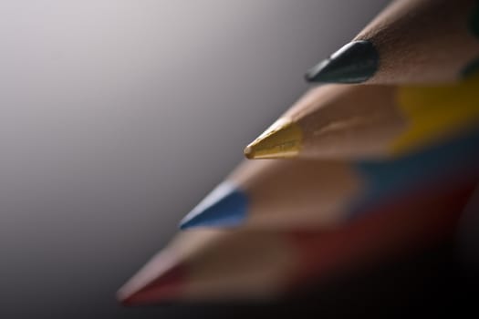 Group of four colored pencils with shallow depth of field on grey background. 