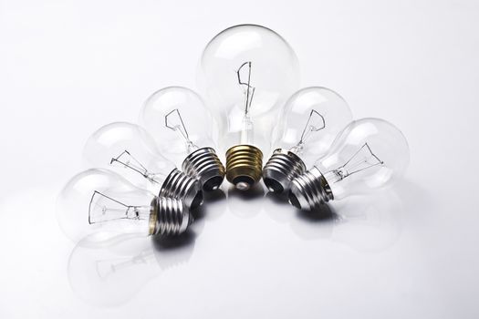 Composition with six light bulbs, one being bigger and having a golden fillet on white background