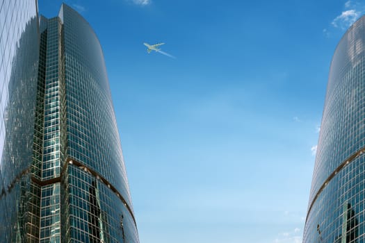 Skyscrapers on blue sky background with jet