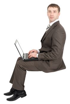 Businessman working on laptop and looking at camera isolated on white background 