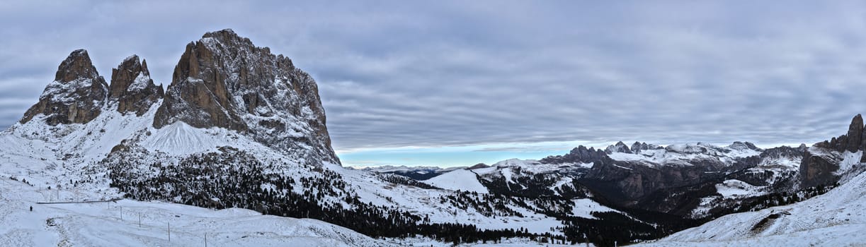 Landscape from Sella Pass in the Dolomiti mountains in a cloudy afternoon with blue sky at the horizon, winter season - Trentino-Alto Adige, Italy