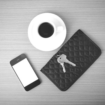 coffee phone key and wallet on wood table background black and white color