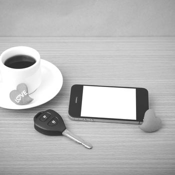 coffee phone car key and heart on wood table background black and white color