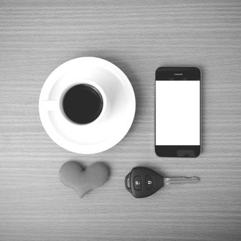 coffee phone car key and heart on wood table background black and white color