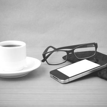 coffee,phone,eyeglasses and wallet on wood table background black and white color