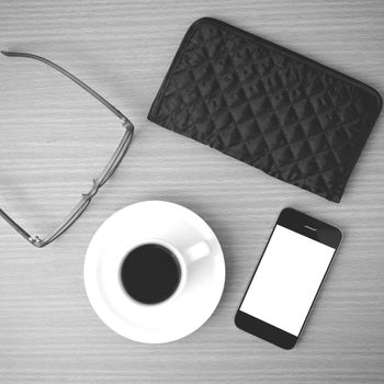 coffee,phone,eyeglasses and wallet on wood table background black and white color