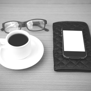 coffee,phone,eyeglasses and wallet on wood table background black and white color