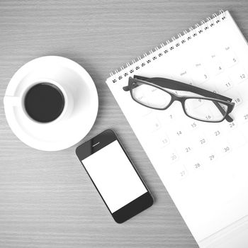 coffee,phone,eyeglasses and calendar on wood table background black and white color