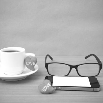 coffee,phone,eyeglasses and heart on wood table background black and white color