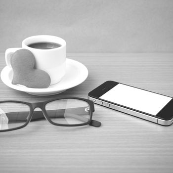 coffee,phone,eyeglasses and heart on wood table background black and white color