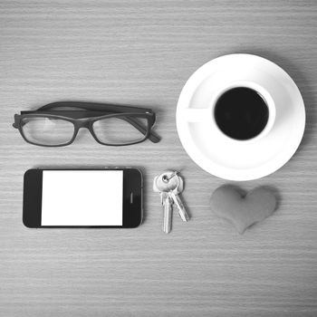 coffee,phone,eyeglasses,key and heart on wood table background black  and white color