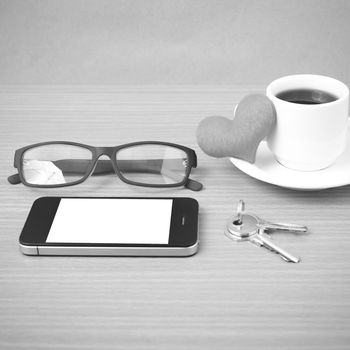 coffee,phone,eyeglasses,key and heart on wood table background black  and white color