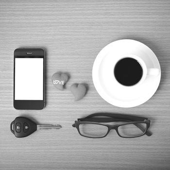 coffee,phone,eyeglasses,car key and heart on wood table background black  and white color