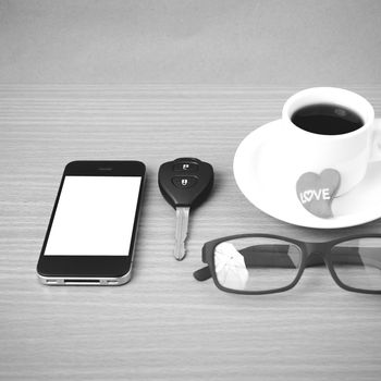 coffee,phone,eyeglasses,car key and heart on wood table background black  and white color