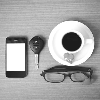 coffee,phone,eyeglasses,car key and heart on wood table background black  and white color