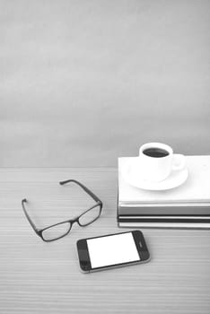 coffee,phone,stack of book and eyeglasses on wood table background black and white color
